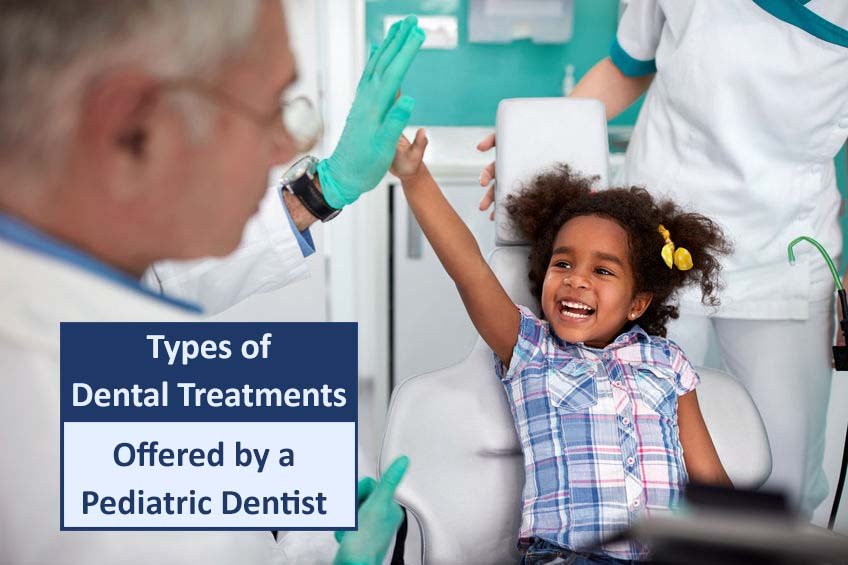 A pediatric dentist high-fiving a smiling young girl sitting in a dental chair, with a dental assistant in the background.